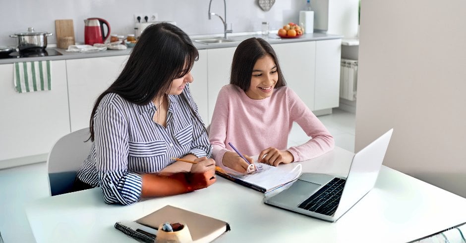 Mother and daughter homeschooling together at the kitchen table