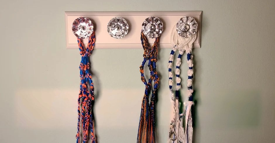 Handmade tzitzit hanging from a wall hook rack