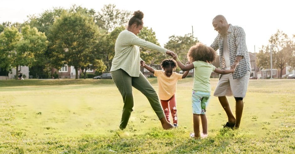 Family playing ring-around-the-rosy in a sunny park